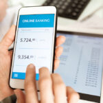 Hands of businessperson with smartphone scrolling through online banking account